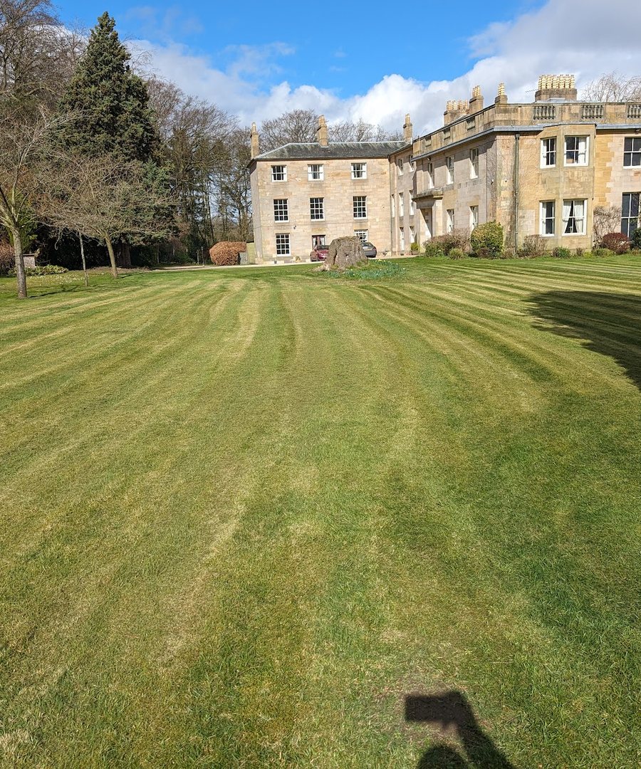 Striped lawns and mature grounds maintained at a country house estate