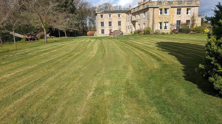 Striped lawns and mature grounds at a country house estate